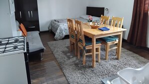 A compact living space with a bed, a dining table with chairs, a kitchenette, and a small seating area. - Studio for rent in Cusco city center! (Cusco)