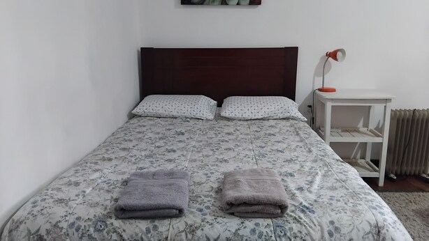 A neatly made bed with floral bedding, two pillows, and two folded towels. - Studio for rent in Cusco city center! (Cusco)