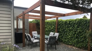 Eine hölzerne Pergola mit Tisch und Stühlen in einem Garten.