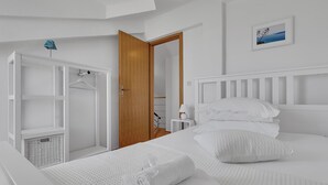 A bedroom with a bed, a wardrobe, a nightstand, and a wall-mounted picture.