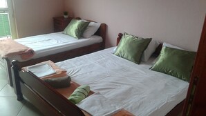 A room with two single beds, each with a pillow and a blanket. There is a wooden nightstand with a plant on it. - Apartment Bella Vista With Sea View Montenegro  (Radovići)