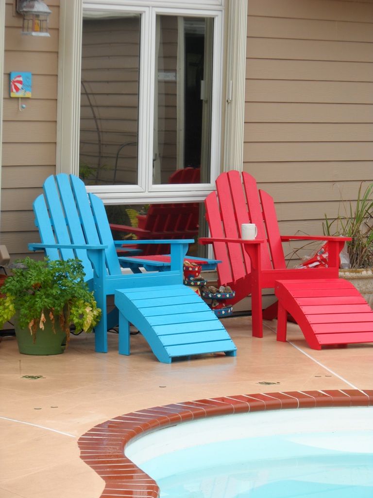 Zona de piscina amb dues cadira Adirondack, una blava i una vermella, i una taula petita.