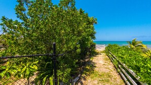 A pathway leading to a beach with lush greenery and a clear blue sky. - Corktree Beach House - Modern, Beachfront 2bd/3ba home with central AC (Grand Turk)