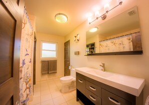 A bathroom with a toilet, sink, vanity, and a shower curtain with a nautical theme. - Corktree Beach House - Modern, Beachfront 2bd/3ba home with central AC (Grand Turk)