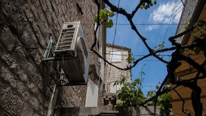 Un passage voûté en pierre, d’où l’on peut apercevoir l’intérieur d’un bâtiment à travers une fenêtre.