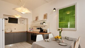 Une cuisine moderne avec des meubles gris, une table à manger dressée avec des assiettes et des tasses, et une grande fenêtre donnant sur un paysage verdoyant.
