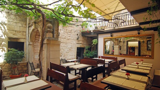 Un espace extérieur aménagé pour les repas, avec des murs en pierre, des tables et des chaises en bois.