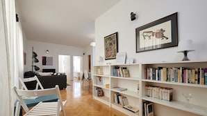 Un salon moderne avec un canapé, une table à manger et des chaises, ainsi qu’une bibliothèque remplie de livres.