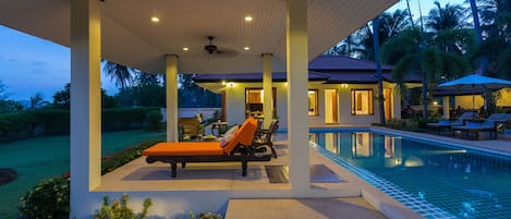 Una piscina al aire libre, sillones reclinables de piscina