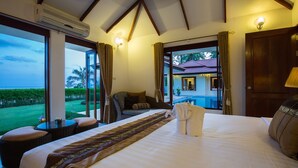 A hotel room with a large bed, a view of the ocean, a balcony, and a dining area.