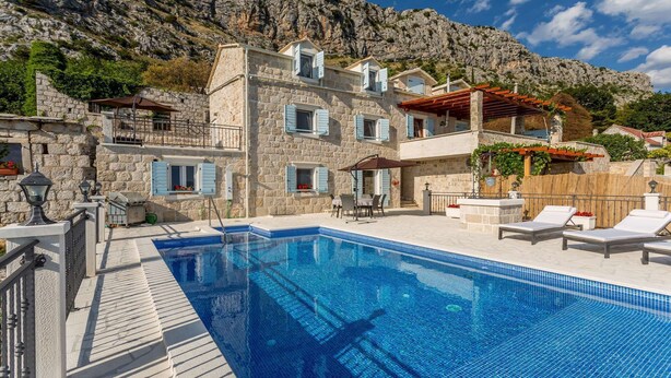 A stone building with a swimming pool, outdoor seating, and a view of a mountainous landscape. - VILLA NARESTE Stone house with pool and amazing sea view (Jesenice)