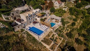 An aerial view of a stone villa with a swimming pool, terraced gardens, and a mountainous backdrop. - VILLA NARESTE Stone house with pool and amazing sea view (Jesenice)