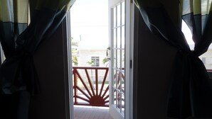 An open balcony door with a view of a building and a railing. - Great location for the adventurous traveler! (Maxwell)