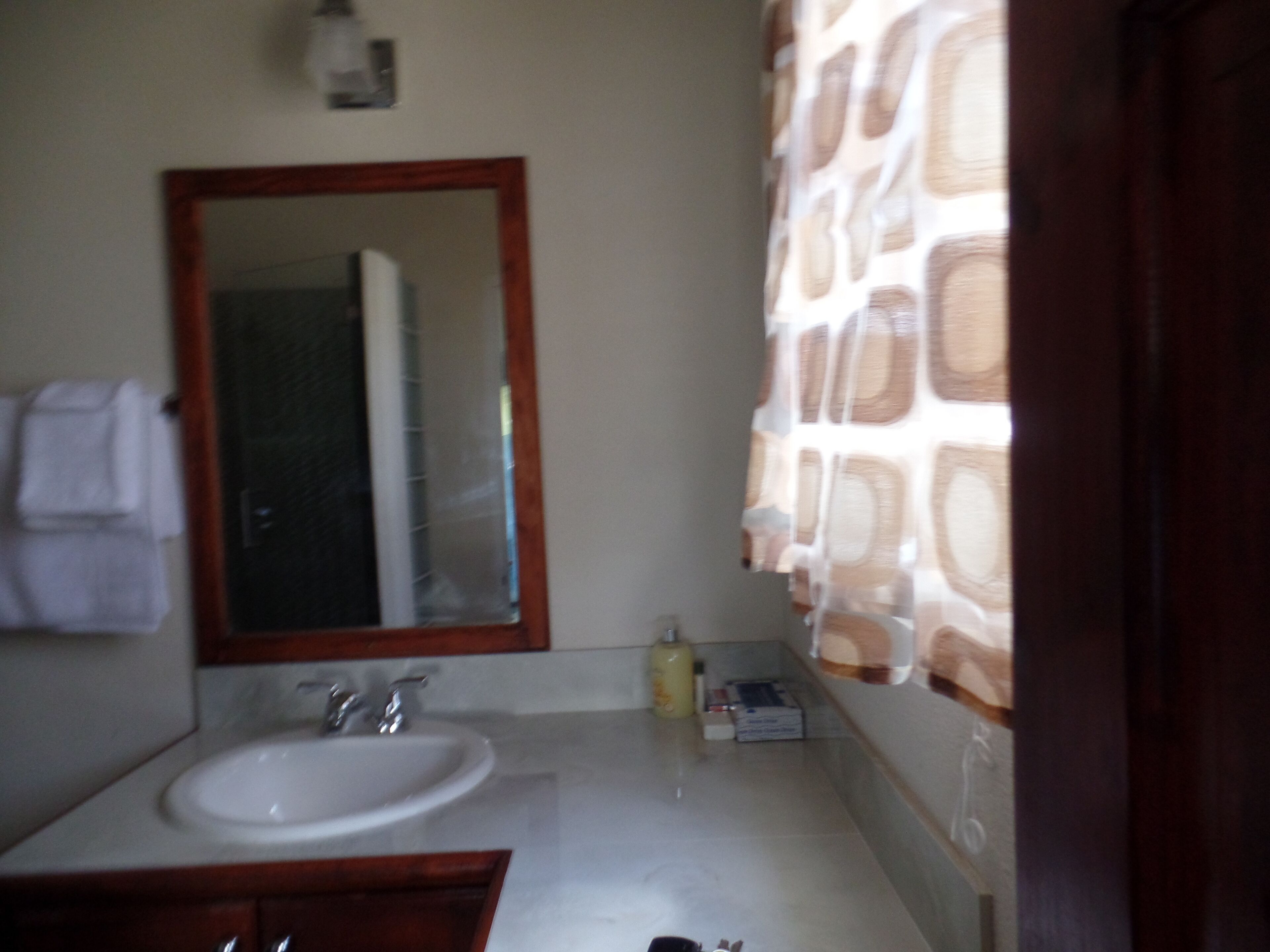 Un baño con lavamanos, espejo y perchero para toallas.