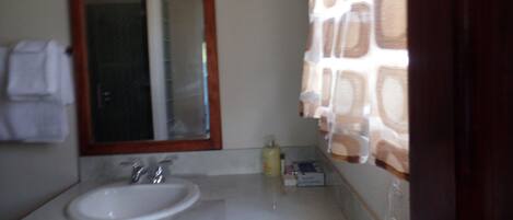 Un baño con lavamanos, espejo y perchero para toallas.