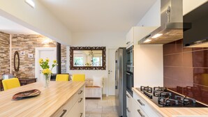 Una cocina moderna con una isla central, electrodomésticos de acero inoxidable y un espejo decorativo.