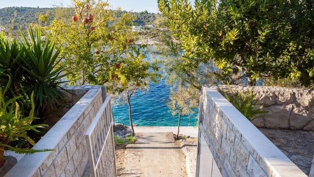A stone staircase leading to a coastal area with a view of the sea and greenery. - Cozy apartment  Bose 2+2 only 5 metres from the beach special discount -30%! (Dvornica, Rogoznica)