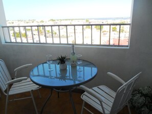A round table with two white chairs, a bottle of champagne, and two wine glasses on a balcony with a view of a cityscape. - A Beautiful Home with a View in Olhao, Algarve (Olhao)