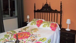 A bedroom with a bed, two bedside tables, and a window with curtains. - A Beautiful Home with a View in Olhao, Algarve (Olhao)