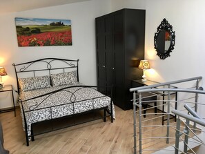 Ein Schlafzimmer mit einem Bett, einem Kleiderschrank, einem Spiegel und einer Lampe.