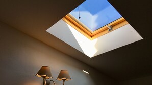 Une lucarne donnant sur le ciel, un lampadaire fixé au plafond et une lampe fixée au mur.