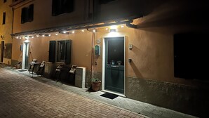 Un bâtiment avec un bar situé au rez-de-chaussée, des places assises en plein air et une porte portant un numéro.