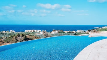 Relax by the infinity pool overlooking the ocean and lush greenery.