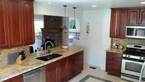 Una cocina con encimeras de granito, armarios de madera, horno empotrado y lavavajillas.