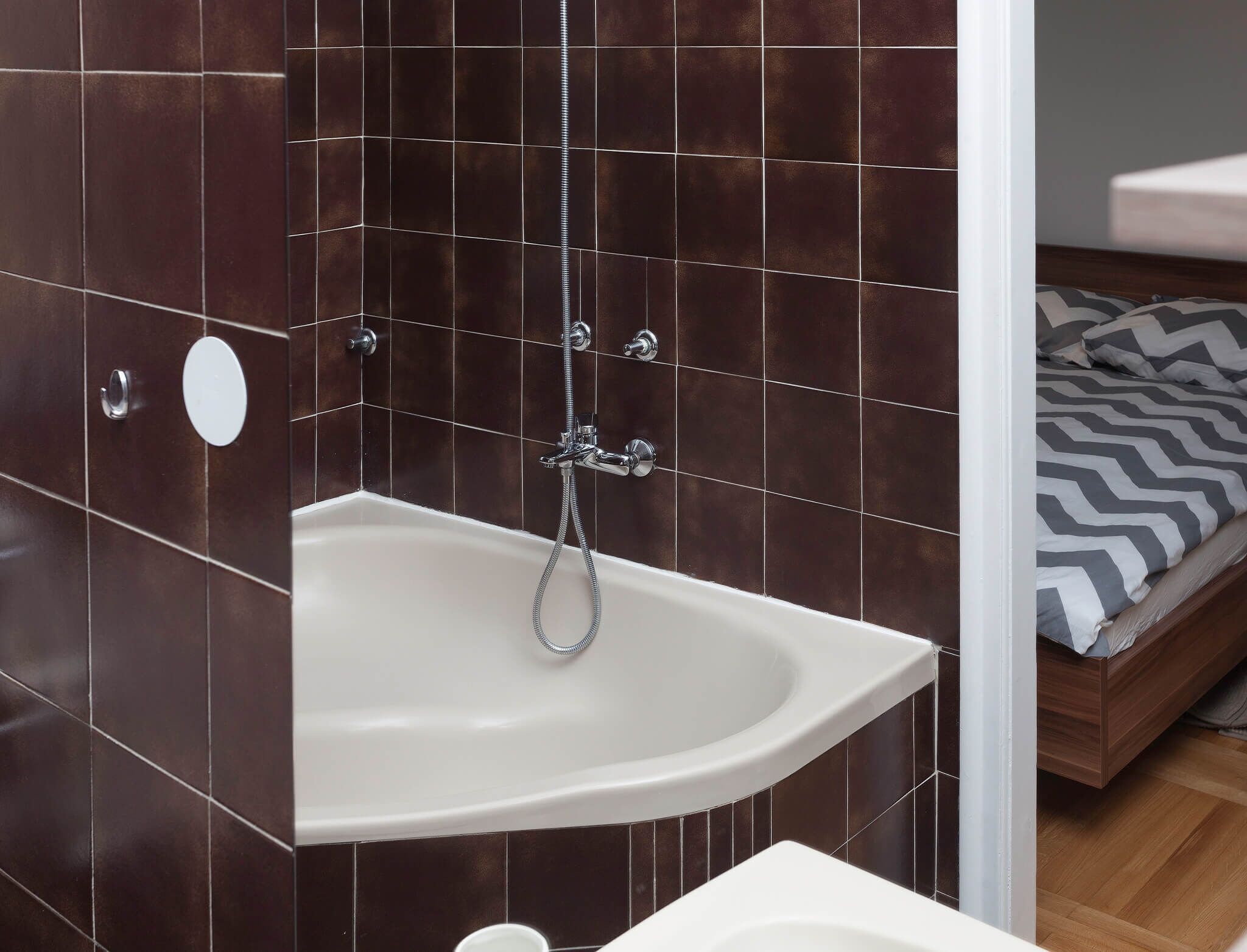 Een badkamer met een witte wastafel, een douche met handdouche en een toilet.