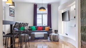 Una sala de estar moderna con un sofá, sillas, una mesa de centro y un televisor montado en la pared.