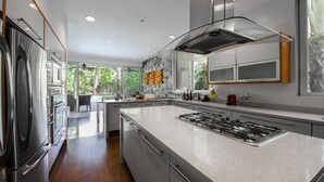 Una cocina moderna con una isla central, electrodomésticos de acero inoxidable y vistas al exterior.