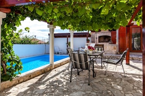 A poolside area with a stone patio, outdoor seating, and a brick oven. - Countryside Family Villa with Private Pool (Donje Selo)