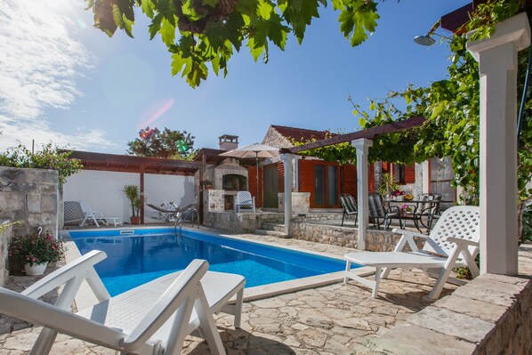 A swimming pool with lounge chairs, a stone patio, and a covered outdoor seating area. - Countryside Family Villa with Private Pool (Donje Selo)