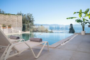 Relax by the serene pool, surrounded by lush greenery and a stunning view.