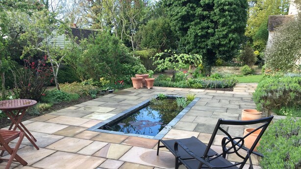 A garden patio with a rectangular pond, stone tiles, and outdoor furniture. - Converted Granary in SE Kent UK (Lyminge, nr Folkestone)