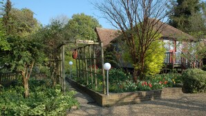 A garden entrance with a wooden archway labeled "The Granary," surrounded by lush greenery and flowering plants. - Converted Granary in SE Kent UK (Lyminge, nr Folkestone)
