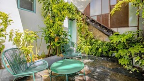 A patio with two green metal chairs, a small table, and a staircase leading to an upper level. - Cave Suite THA (Cave Hotel Lomas de Ruvira) (Jorquera)