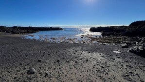 A rocky beach with clear skies and the sun shining.