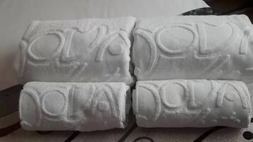 Cuatro toallas enrolladas con texto en relieve, sobre un tejido estampado.