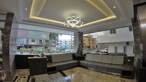 A hotel lobby with a large seating area, a Christmas tree, and a view of the street outside. - Nova Hotel Miri (Miri)