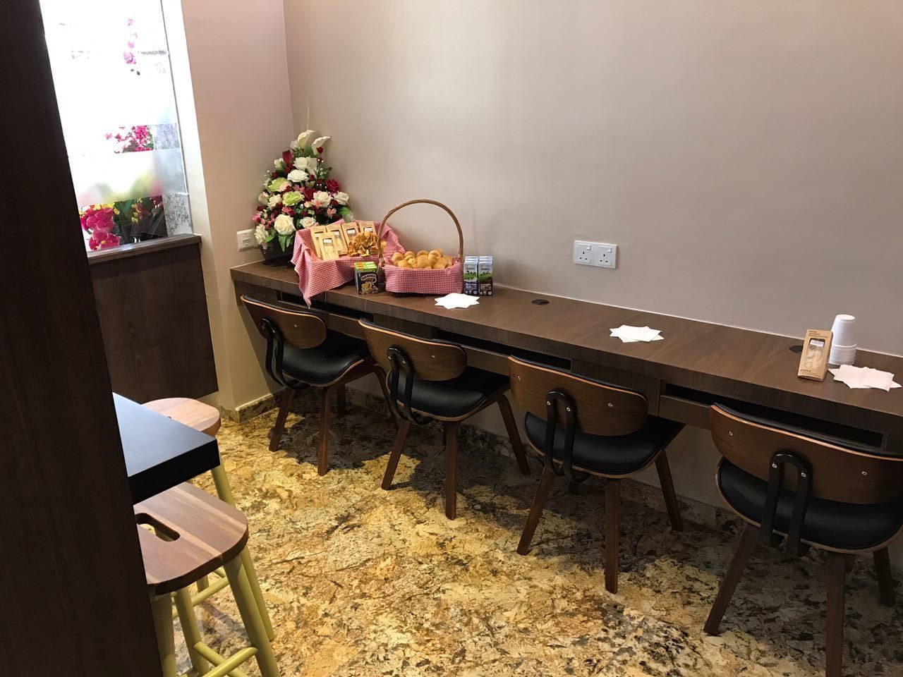 A long dining table with six chairs, a floral arrangement, and a basket of bread on the table.