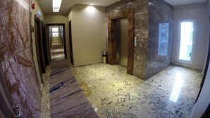 A hotel corridor with marble flooring, a wooden elevator, and a glass door leading to a balcony. - Nova Hotel Miri (Miri)