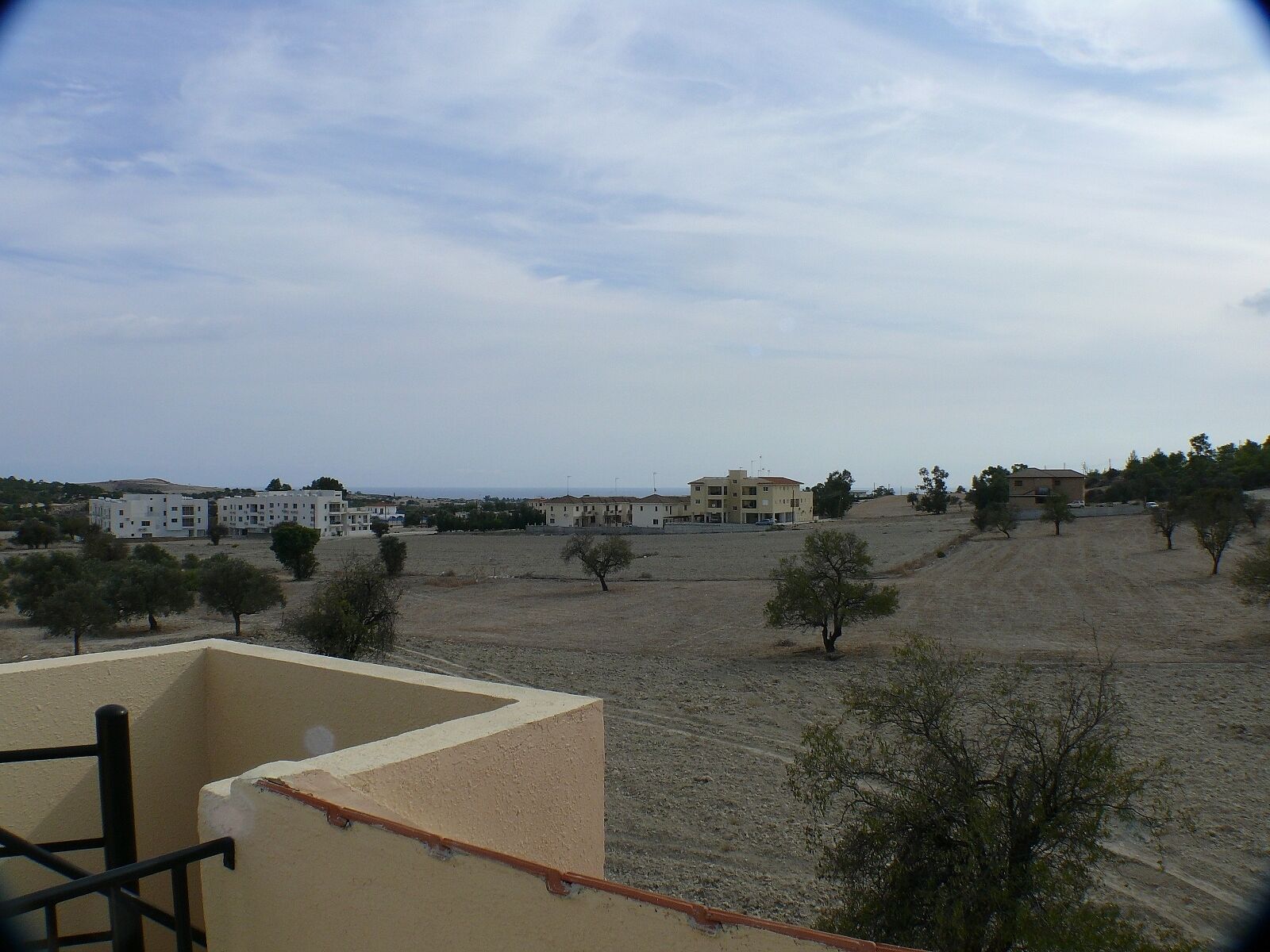 Zona residencial con edificios, campos abiertos y pocos árboles.