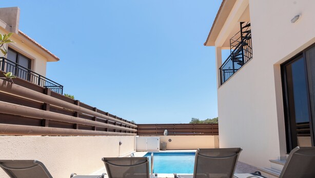 A poolside area with lounge chairs and a pool. - 4 Bedroom Villa With Private Pool (Alethriko)