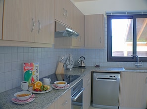 Enjoy a home-cooked meal in this fully equipped kitchen with a window offering a view of the outside.
