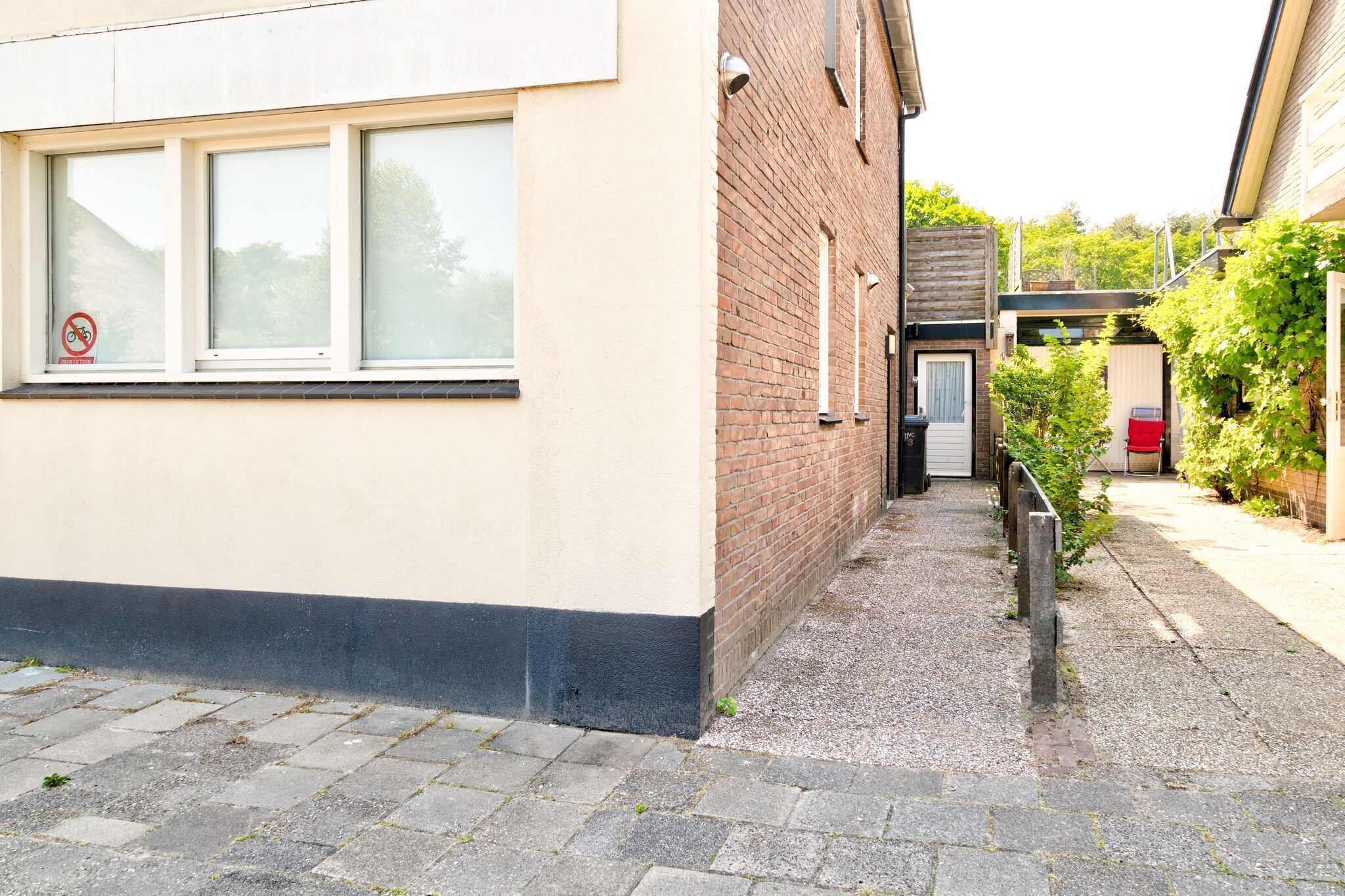 A narrow alleyway with a building on the left and a brick wall on the right.