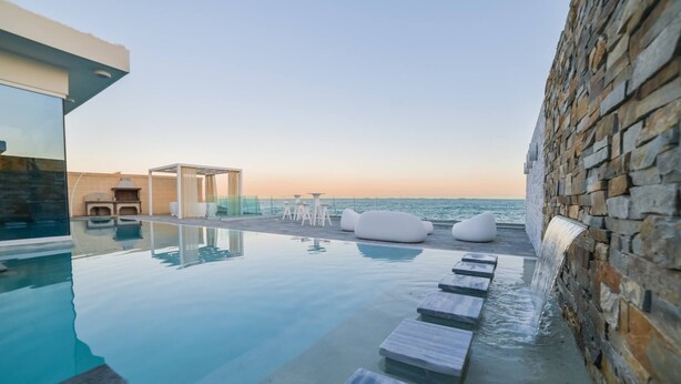A rooftop infinity pool with a clear view of the ocean, stone walls, and outdoor seating. - Spectacular Sea-View Villa with Spa Area (Marsaskala)