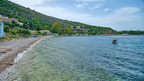Zona costera con playa de guijarros, agua cristalina y un bote.