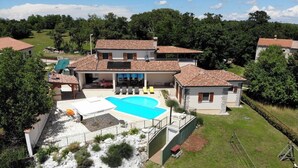 Propiedad residencial con piscina, zona de estar exterior y jardín con un elemento rocoso.