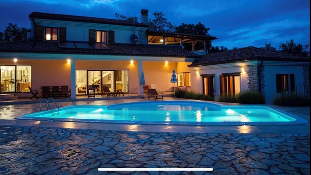 Una casa de dos pisos con piscina, mobiliario de exterior y un porche cubierto.